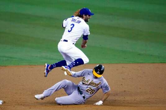 Los Angeles Dodgers second baseman Chris Taylor hops over Oakland Athletics' Matt Olson, who was forced out on a double play hit into by Ramon Laurean during the second inning of a baseball game Thursday, Sept. 24, 2020, in Los Angeles. (AP Photo/ Marcio Jose Sanchez)