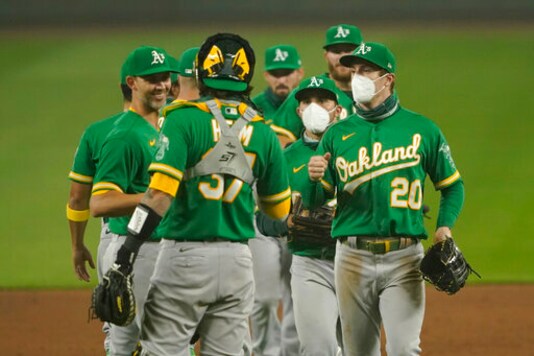 Oakland Athletics outfielders Mark Canha (20) and Ramon Laureano, second from right, wear masks as they greet teammates after they defeated the Seattle Mariners in the second baseball game of a doubleheader, Monday, Sept. 14, 2020, in Seattle. Both games were played in air smoky from wildfires in Oregon, Washington, and California. (AP Photo/Ted S. Warren) Oakland Athletics outfielders Mark Canha (20) and Ramon Laureano, second from right, wear masks as they greet teammates after they defeated the Seattle Mariners in the second baseball game of a doubleheader, Monday, Sept. 14, 2020, in Seattle. Both games were played in air smoky from wildfires in Oregon, Washington, and California. (AP Photo/Ted S. Warren)