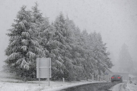 A car makes his way through heavy snow fall on motorway A 13 in Noesslach near Innsbruck, Austria, Friday, Sept. 25, 2020. (AP Photo/Matthias Schrader)