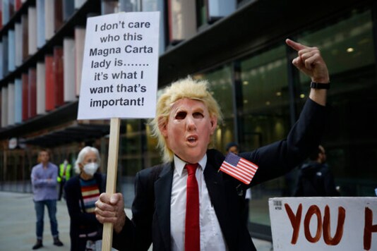 A supporters of WikiLeaks founder Julian Assange wearing a mask portraying U.S. President Donald Trump takes part in a protest outside the Central Criminal Court, the Old Bailey, in London, Monday, Sept. 14, 2020. The London court hearing on WikiLeaks founder Julian Assange's extradition from Britain to the United States resumed Monday after a COVID-19 test on one of the participating lawyers came back negative, WikiLeaks said Friday. (AP Photo/Matt Dunham)