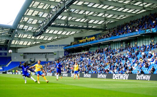 Brighton soccer fans adhere to social distancing measures in the stands as they watch the action on the pitch during the pre-season friendly between Brighton and Chelsea,  at the AMEX Stadium in Brighton, England, Saturday, Aug. 29, 2020. Up to 2500 fans have been allowed in to watch the match after the government announced a further batch of sporting events that will be used to pilot the safe return of spectators. (Adam Davy/PA via AP)