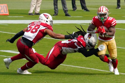 San Francisco 49ers running back Jerick McKinnon (28) runs against Arizona Cardinals middle linebacker Jordan Hicks (58) and outside linebacker De'Vondre Campbell during the first half of an NFL football game in Santa Clara, Calif., Sunday, Sept. 13, 2020. (AP Photo/Tony Avelar)