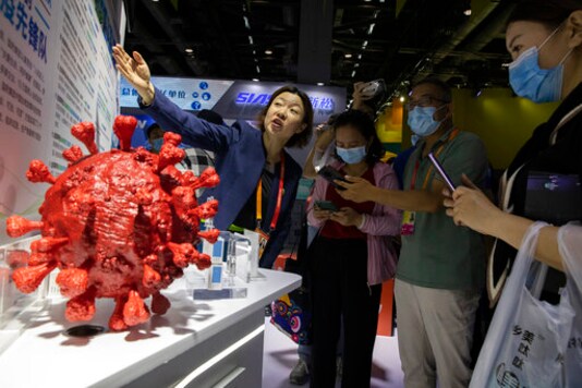 An employee answers questions from the public near samples of a COVID-19 vaccine produced by Sinopharm subsidiary CNBG are displayed during a trade fair in Beijing on Sept. 6, 2020. State-backed Sinopharm's subsidiary CNBG has injected 350,000 people outside its clinical trials for COVID-19 vaccine, which have about 40,000 people enrolled. It's a highly unusual move that raises ethical and safety questions, as companies and governments worldwide race to develop a vaccine that will stop the spread of the new coronavirus. (AP Photo/Ng Han Guan)