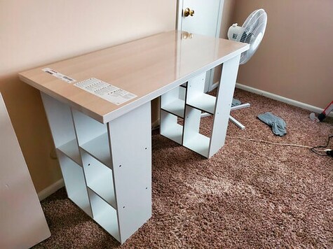 In this photo provided by Megan Fry, a desk Fry constructed out of a legless tabletop and bookcases stands in her Indianapolis home on Sept. 14, 2020. First it was toilet paper. Disinfectant wipes. Beans. Coins. Computers. Now, desks are in short supply because of the coronavirus pandemic. Its not as cute or trendy as a bought desk and I wish it had drawers for storage, said Fry, who is starting a new work-from-home customer service job in Indianapolis in October.  But Im happy its clean and has a large surface on top for my monitors and laptop. (Megan Fry via AP)