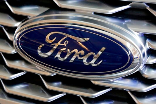 FILE- This Feb. 15, 2018, file photo shows a Ford logo on the grill of a 2018 Ford Explorer on display at the Pittsburgh Auto Show.  Ford Motor Co. will offer early retirement incentives with hopes of cutting its U.S. white-collar workforce by 1,400 more positions. President for the Americas Kumar Galhotra told employees about the offers Wednesday, Sept. 2, 2020.   (AP Photo/Gene J. Puskar, File)