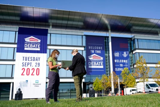 FILE - In this Sunday, Sept. 27, 2020, file photo, women go over a playbook while setting up outside of the Health Education Campus of Case Western Reserve University in Cleveland, ahead of the first presidential debate between Republican President Donald Trump and Democratic candidate and former Vice President Joe Biden. Some of the countrys major sports betting companies are running contests in which participants predict things that will happen or be said during the presidential debate, Tuesday, Sept. 29, 2020, for the chance to win money. (AP Photo/Julio Cortez, File)