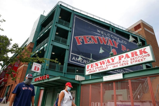 FILE - In this July 24, 2020, file photo, two fans walk on a normally crowded Jersey Street in front of Fenway Park before an opening day baseball game between the Boston Red Sox and the Baltimore Orioles. Elections officials in Boston are expected to approve Fenway Park as an early voting venue when they meet on Thursday, Sept. 24, after Red Sox owner John Henry offered the storied ballpark for voters hesitant to cast ballots indoors during the coronavirus pandemic. (AP Photo/Michael Dwyer, File)