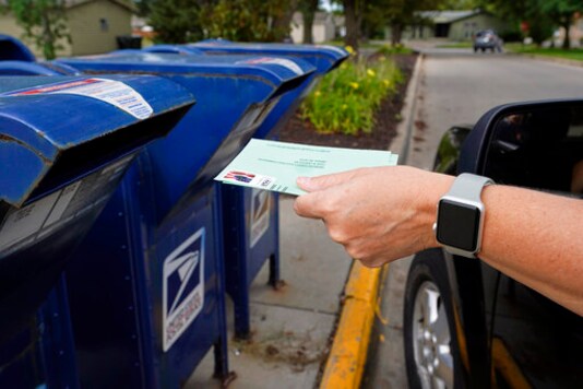 FILE - In this Tuesday, Aug. 18, 2020, file photo, a person drops applications for mail-in-ballots into a mailbox in Omaha, Neb. Data obtained by The Associated Press shows Postal Service districts across the nation are missing the agencys own standards for on-time delivery as millions of Americans prepare to vote by mail. (AP Photo/Nati Harnik, File) FILE - In this Tuesday, Aug. 18, 2020, file photo, a person drops applications for mail-in-ballots into a mailbox in Omaha, Neb. Data obtained by The Associated Press shows Postal Service districts across the nation are missing the agencys own standards for on-time delivery as millions of Americans prepare to vote by mail. (AP Photo/Nati Harnik, File)