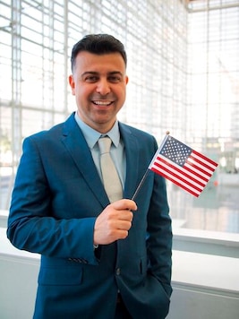 This September 2019 photo provided by Danielle Luna, shows Iraqi born refugee Bilal Alobaidi at his naturalization ceremony. Alobaidi, who arrived in the U.S. in December 2013, was resettled in Phoenix, a desert city with sweltering weather similar to that of native Mosul. The former social worker with the International Organization of Migration in Iraq now works for the nongovernmental group International Rescue Committee in Arizona, helping newly arrived refugees find apartments and jobs. (Danielle Luna via AP)
