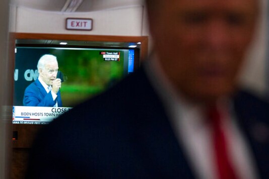 A television screen shows Democratic presidential candidate former Vice President Joe Biden holding up a mask, as President Donald Trump talks with reporters on Air Force One while returning to Washington after a campaign rally at Central Wisconsin Airport, Thursday, Sept. 17, 2020. (AP Photo/Evan Vucci)