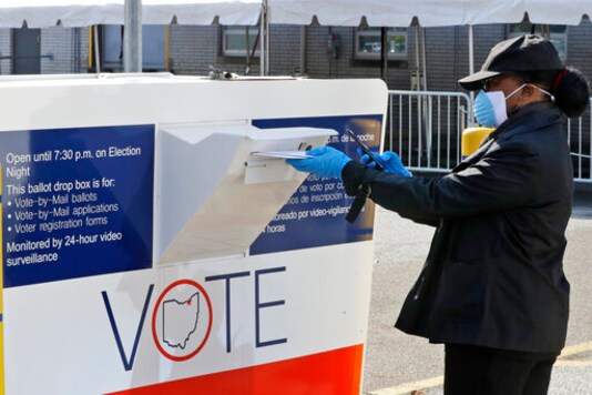 FILE  In this April 28, 2020 file photo, Marcia McCoy drops her ballot into a box outside the Cuyahoga County Board of Elections in Cleveland, Ohio. A county judge ruled Tuesday, September 15, 2020 that Ohio Secretary of State Frank LaRose's directive restricting counties to providing just one ballot drop box in November was 
