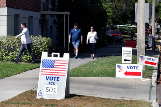 FILE - In this March 17, 2020 file photo, voters head to a polling station to vote in Florida's primary election in Orlando, Fla.    Florida felons must pay all fines, restitution and legal fees before they can regain their right to vote, a federal appellate court ruled Friday, Sept, 11. Reversing a lower court judge's decision that gave Florida felons the right to vote regardless of outstanding legal obligations, the order from the U.S. 11th Circuit Court of Appeals was a disappointment to voting rights activists and could have national implications in Novembers presidential election.  (AP Photo/John Raoux, File)