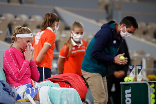 Petra Kvitova of the Czech Republic wipes her nose as an official, right, tests the balls in the first round match of the French Open tennis tournament against France's Oceane Dodin at the Roland Garros stadium in Paris, France, Monday, Sept. 28, 2020. (AP Photo/Alessandra Tarantino)