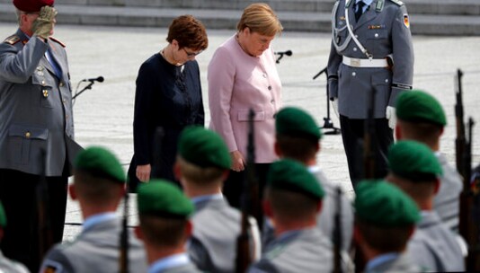 FILE -- In this Saturday, July 20, 2019 file photo German Chancellor Angela Merkel, center right, and German Defence Minister Annegret Kramp-Karrenbauer, center left, bow in front of soldiers during an oath-taking ceremony of the German army at the Defence Ministry in Berlin, Germany. Germany's defense minister is apologizing for decades of discrimination against gay servicepeople in the military until a change of policy in 2000. A study commissioned by the defense ministry and being presented Thursday documented systematic discrimination from 1955 until the end of the 20th century. (AP Photo/Michael Sohn)