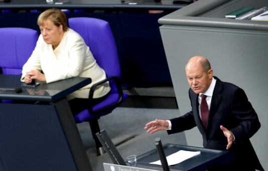 German Finance Minister Olaf Scholz, right, delivers a speech during a budget debate as part of a meeting of the German federal parliament, Bundestag, at the Reichstag building in Berlin, Germany, Tuesday, Sept. 29, 2020. At left is German Chancellor Angela Merkel. (AP Photo/Michael Sohn)