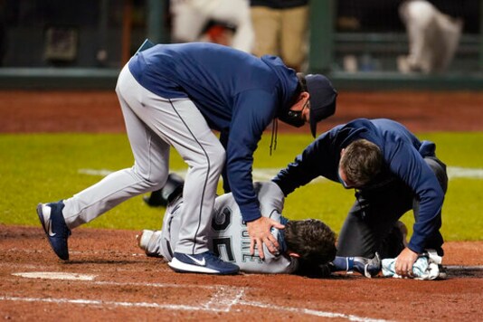 Seattle Mariners manager Scott Servais, left, and a trainer check on Dylan Moore after he was hit by a pitch from San Francisco Giants' Sam Coonrod during the seventh inning of a baseball game in San Francisco, Wednesday, Sept. 16, 2020. (AP Photo/Jeff Chiu) Seattle Mariners manager Scott Servais, left, and a trainer check on Dylan Moore after he was hit by a pitch from San Francisco Giants' Sam Coonrod during the seventh inning of a baseball game in San Francisco, Wednesday, Sept. 16, 2020. (AP Photo/Jeff Chiu)