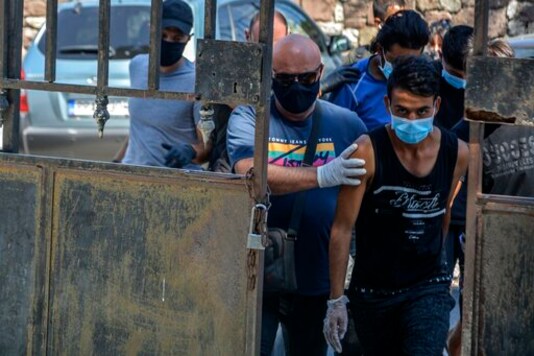 Suspects, all from Afghanistan escorted by plain clothes policemen and wearing face masks, arrive at a court in Mytilene, the capital of the northeastern Aegean island of Lesbos, Greece, Wednesday, Sept. 16, 2020. The government says the fires in Moria refugee camp were set deliberately by the Afghan migrants protesting a coronavirus lockdown, and authorities on Tuesday announced the arrests of six suspect, include two 17-year-olds, in the case. (AP Photo/Panagiotis Balaskas)