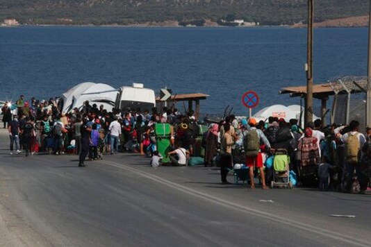 Migrants wait to enter a new temporary refugee camp in Kara Tepe, near Mytilene the capital of the northeastern island of Lesbos, Greece, Thursday, Sept. 17, 2020. Greek police are moving hundreds of migrants to an army-built camp on the island of Lesbos Thursday after a fire destroyed an overcrowded facility, leaving them homeless for days. (AP Photo/Petros Giannakouris)