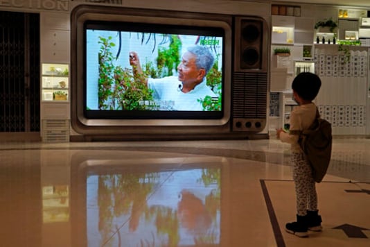 A TV screen shows a footage of Arthur Lee, owner of the MoVertical Farm, at a supermarket in Hong Kong Thursday, Sept. 24, 2020. Operating on a rented 1,000 square meter patch of wasteland in Hong Kong's rural Yuen Long, Arthur Lee's MoVertical Farm utilizes around 30 of the decommissioned containers, to raise red water cress and other local vegetables hydroponically, which eliminates the need for soil. A few are also used as ponds for freshwater fish, with the bounty sold to local supermarkets in this crowded city of 7.5 million that is forced to import most of its food. (AP Photo/Kin Cheung)