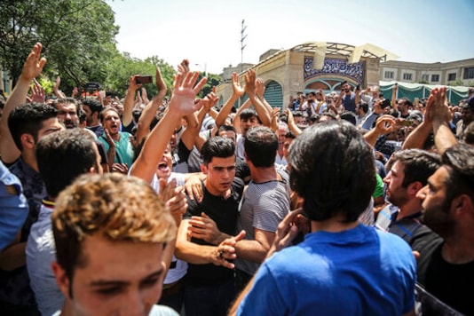 FILE - In this June 25, 2018 file photo, a group of protesters chant slogans at the main gate of the Old Grand Bazaar, in Tehran, Iran. On Saturday, Sept. 5, 2020, Iran broadcast the televised confession of a wrestler facing the death penalty after a tweet from President Donald Trump criticizing the case, a segment that resembled hundreds of other suspected coerced confessions aired over the last decade in the Islamic Republic. The case of 27-year-old Navid Afkari has drawn the attention of a social media campaign that portrays him and his brothers as victims targeted over participating in protests against Iran's Shiite theocracy in 2018. (Iranian Labor News Agency via AP, File)