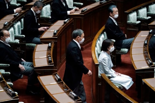 Japan's new Prime Minister Yoshihide Suga walks in to attend an extraordinary session at the upper house of parliament Thursday, Sept. 17, 2020, in Tokyo. Suga started his first full day in office Thursday, with a resolve to push for reforms for the people, and he said he is already taking a crack at it. (AP Photo/Eugene Hoshiko)