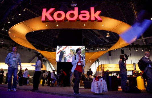FILE - In this Jan. 11, 2012 file photo, buyers and industry affiliates pass by the Kodak exhibit at the 2012 International CES trade show in Las Vegas.  An independent legal review has determined that there were several flaws in how Eastman Kodak gave stock option grants to its CEO prior to the once formidable photography company being awarded a loan from the Trump administration.  (AP Photo/Julie Jacobson, File)