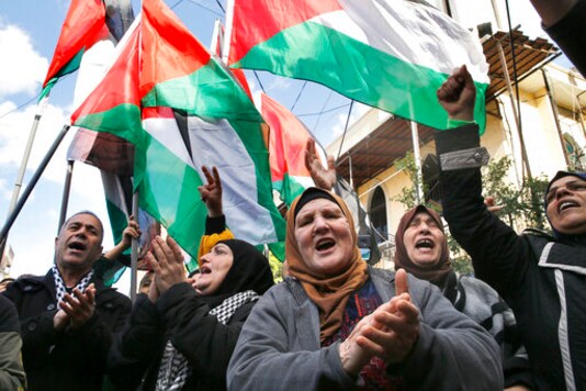 FILE - This Friday, Jan. 31, 2020 file photo, Palestinians chant slogans as they hold Palestinian flags, during a protest against the White House plan for ending the Israeli-Palestinian conflict, at Burj al-Barajneh refugee camp, south of Beirut, Lebanon. The financial crisis that the U.N. agency for Palestinian refugees is experiencing could lead to ceasing some of its activities in what would raise risks of instability in this volatile region, the head of the agency said Wednesday, Sept. 16. (AP Photo/Bilal Hussein, File)