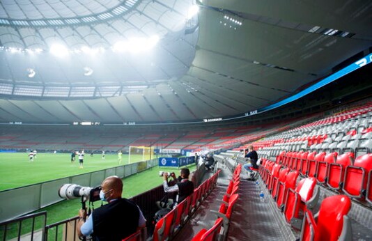 Smoke fills the air as a handful of photographers are seated amongst the empty seating of B.C. Place during the first half of an MLS soccer game between the Vancouver Whitecaps and the Montreal Impact, Sunday, Sept. 13, 2020 in Vancouver, British Columbia. (Jonathan Hayward/The Canadian Press via AP)