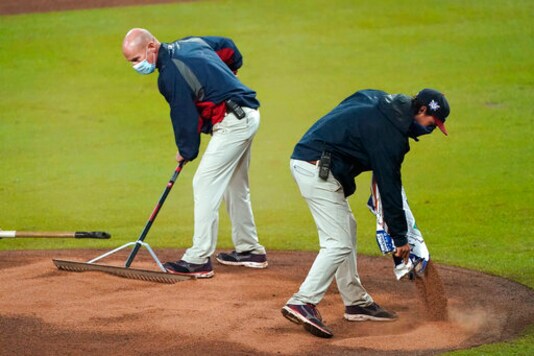 Members of the Atlanta Braves grounds crew work to repair the mound during a rain shower in the fourth inning of a baseball game between the Atlanta Braves and the Miami Marlins on Thursday, Sept. 24, 2020, in Atlanta. (AP Photo/John Bazemore)