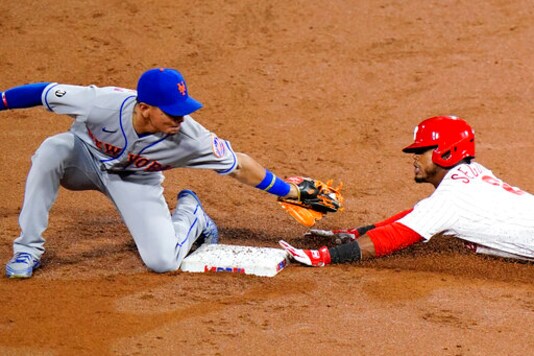 Philadelphia Phillies' Jean Segura, right, slides under the tag of New York Mets shortstop Andres Gimenez for a double during the second inning of a baseball game, Wednesday, Sept. 16, 2020, in Philadelphia. (AP Photo/Matt Slocum)