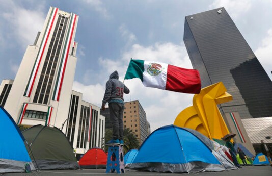 A protester waves a Mexican flag to demand the resignation of Mexican President Andrs Manuel Lpez Obrador, commonly known by his initials AMLO, during a sleep-in protest at the intersection of Avenida Juarez and Reforma in Mexico City, Tuesday, Sept. 22, 2020. The protesters organized by the National Front against AMLO or National Front Against AMLO decided to camp on the street, completely blocking Juarez Avenue. (AP Photo/Marco Ugarte)