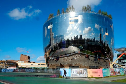 A person walks past the new Depot Boijmans Van Beuningen in Rotterdam, Netherlands, Thursday Sept. 24, 2020. The Museum Boijmans Van Beuningen in Rotterdam has a shimmering new depot that is designed to open up the institution's engine room to the public. The mirrored building will give visitors access to the vast majority of the museum's collection of 151,000 art works that currently are stored out of the public eye. (AP Photo/Mike Corder)