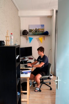 Dutch physics student David Hintzen looks at his laptop in his room in a shared house in Leiden, Netherlands on Friday, Sept. 25, 2020. The coronavirus pandemic is hitting students hard in Leiden, the Netherlands' oldest university city. With the virus casting a long shadow over education here and around the world, most lectures are online and the vibrant social life has been reined in to slow the spread of the pandemic. (AP Photo/Mike Corder)