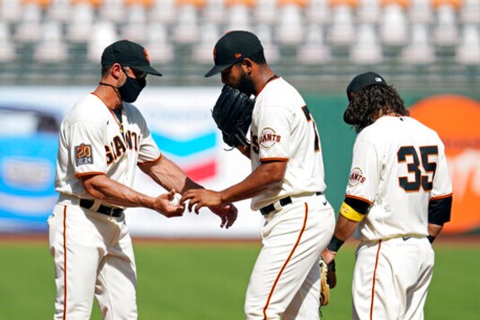 San Francisco Giants relief pitcher Jarlin Garca hands the ball to manager Gabe Kapler, left, and leaves the game in the seventh inning of a baseball game against the San Diego Padres Sunday, Sept. 27, 2020, in San Francisco. At right is Giants shortstop Brandon Crawford (35). (AP Photo/Eric Risberg)