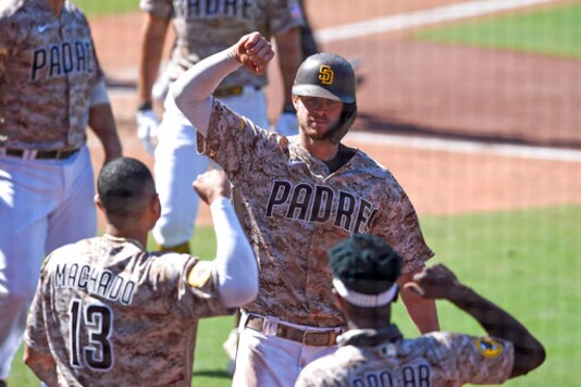 San Diego Padres' Wil Myers (4) is congratulated by Manny Machado (13) and Jurickson Profar (10) after hitting a three-run home run during the sixth inning of a baseball game against the Seattle Mariners Sunday, Sept. 20, 2020, in San Diego. (AP Photo/Denis Poroy)
