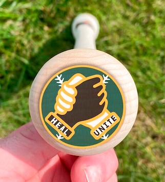 In this photo provided by Hall of Fame shortstop Barry Larkin, Joel Armbruster, the CEO of Phoenix Bats, displays a bat label from Larkin's Project Unity initiative in Plain City, Ohio, Tuesday, Sept. 22, 2020. Major League Baseball has endorsed players putting the label on knobs of bats during the playoff games starting Tuesday, Sept 29, 2020. (Joel Armbruster via AP) In this photo provided by Hall of Fame shortstop Barry Larkin, Joel Armbruster, the CEO of Phoenix Bats, displays a bat label from Larkin's Project Unity initiative in Plain City, Ohio, Tuesday, Sept. 22, 2020. Major League Baseball has endorsed players putting the label on knobs of bats during the playoff games starting Tuesday, Sept 29, 2020. (Joel Armbruster via AP)
