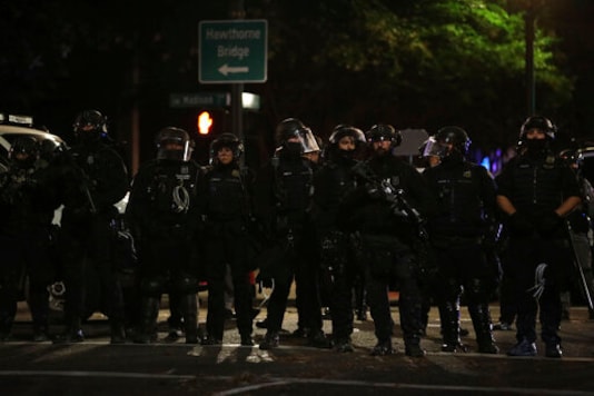 Portland Police line up to block from the street from protesters rallying at the Mark O. Hatfield United States Courthouse on Saturday, Sept. 26, 2020, in Portland, Ore. (AP Photo/Allison Dinner) Portland Police line up to block from the street from protesters rallying at the Mark O. Hatfield United States Courthouse on Saturday, Sept. 26, 2020, in Portland, Ore. (AP Photo/Allison Dinner)