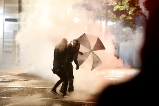 Protesters demanding the end of police violence against Black people take cover from smoke during a demonstration in Portland, Ore., on Wednesday, Sept. 23, 2020. Protesters in Portland hurled Molotov cocktails at officers in Oregon's largest city during a demonstration over a Kentucky grand jury's decision to not indict officers in the fatal shooting of Breonna Taylor, police said Thursday. (Mark Graves/The Oregonian via AP)