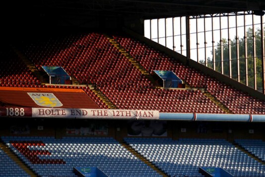 FILE - In this Monday, Sept. 21, 2020 file photo, the sun illuminates the empty stands before the English Premier League soccer match between Aston Villa and Sheffield United at the Villa Park stadium in Birmingham, England. Every empty seat in a Premier League stadium represents a visual reminder of the financial struggle many soccer teams are facing amid the coronavirus pandemic. For smaller soccer teams without TV contracts and huge fan bases, empty seats at matches amid the pandemic can have devastating financial implications. (Tim Goode/Pool via AP, File)