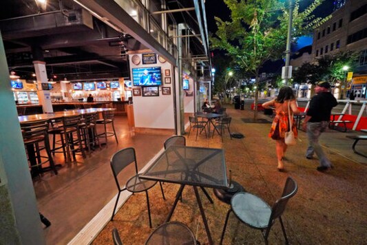 FILE - In this Sept, 9, 2020, file photo, a couple walk past Mike's Beer Bar, across the street from PNC Park, after a baseball game between the Chicago White Sox and Pittsburgh Pirates in Pittsburgh. Small businesses around PNC Park and other downtown stadiums across Major League Baseball are struggling due to the COVID-19 pandemic, which forced MLB to ban fans from attending games during the truncated 2020 seasons. (AP Photo/Gene J. Puskar, File)