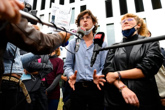 Pro-climate activists Paul Castelain, left, and.Claire Corbaz, right, talk to media after the guilty verdict of the trial of 12 pro-climate activists of the LAC collective (Lausanne Action Climat) that were prosecuted in appeal for organizing a tennis game in a Lausanne branch of Swiss bank Credit Suisse, in front of the court in Renens, Switzerland, Thursday, Sept. 24, 2020. (Laurent Gillieron/Keystone via AP)