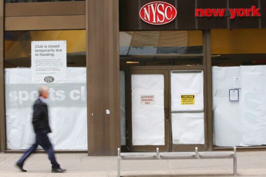 FILE - In this Feb. 7, 2013 photo, a man walks past a shuttered New York Sports Club on Water St. in New York. Town Sports International Holdings Inc., the owner of New York Sports Club and Lucille Roberts filed for Chapter 11 bankruptcy Monday, Sept. 14, 2020, as gym operators struggle to keep afloat amid nationwide shutdowns. (AP Photo/Mary Altaffer, File)