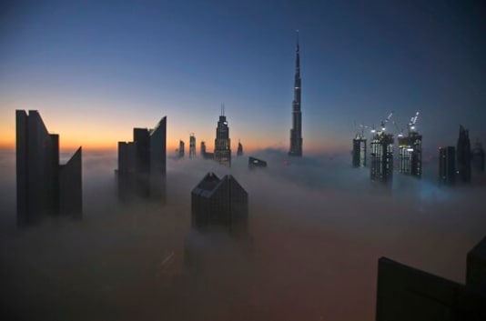 FILE - In this Dec. 31, 2016 file photo, the sun rises over the city skyline with the Burj Khalifa, the world's tallest building, on a foggy day in Dubai, United Arab Emirates. Dubai is tapping the global financial market to potentially raise billions of dollars for the first time in years. That's according to a bond prospectus seen on Tuesday, Sept. 1, 2020, by The Associated Press. It reveals the deepening toll of the coronavirus pandemic on Dubai's economy. (AP Photo/Kamran Jebreili, File)