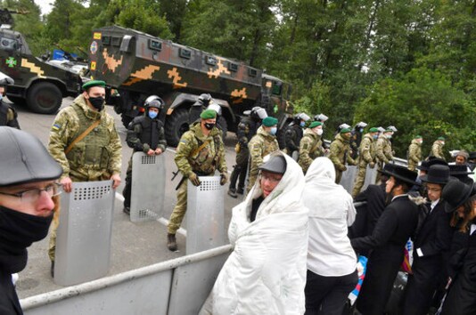 Hasidic Jewish pilgrims gather in front of Ukrainian border guards at the checkpoint Novaya Guta near Novaya Guta, Belarus, Friday, Sept. 18, 2020. Ukrainian officials say that thousands of Hasidic Jewish pilgrims stuck on the Ukrainian border due to coronavirus restrictions have started turning back. About 2,000 ultra-Orthodox Jewish pilgrims traveled to Belarus's border with Ukraine in hope of traveling to the Ukrainian city of Uman to visit the grave of an important Hasidic rabbi who died in 1810, Nachman of Breslov. (AP Photo)