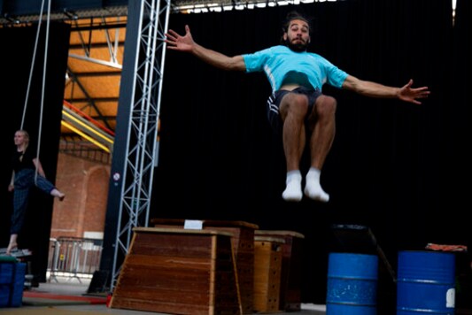 Student Lotke Janssens, left, practices on the aerial straps as Marius Broucke, right, practices his floor acrobatics at the Ell Circo D'ell Fuego circus school in Antwerp, Belgium, Friday, Sept. 18, 2020. The non-traditional school is a collective where young people who are interested in circus performance can further grow and train before showing their skills to an audience. (AP Photo/Virginia Mayo)
