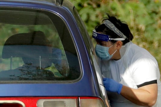 A person is tested for COVID-19 at a drive-through testing centre in a car park at Chessington World of Adventures, in Chessington, Greater London, Saturday, Sept. 19, 2020. England is preparing for more restrictions on gatherings and other activities in several areas of the country. There is growing speculation Britain may be sliding toward a lockdown in the coming weeks, partly because the testing regime is struggling to cope with higher demand. (AP Photo/Matt Dunham)