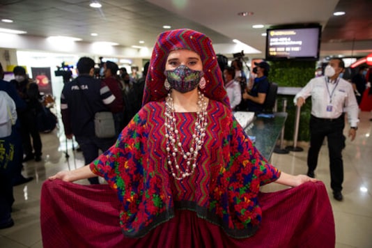 A model from the Guatemalan Tourism Institute poses for photographers wearing an indigenous ceremonial costume during the reopening of La Aurora International Airport in Guatemala City, Friday, Sept. 18, 2020. Guatemala reopened its borders Friday, and is allowing commercial flights from La Aurora that had been restricted to humanitarian and cargo flights since closing its borders in March due to the COVID-19 pandemic. (AP Photo/Moises Castillo) A model from the Guatemalan Tourism Institute poses for photographers wearing an indigenous ceremonial costume during the reopening of La Aurora International Airport in Guatemala City, Friday, Sept. 18, 2020. Guatemala reopened its borders Friday, and is allowing commercial flights from La Aurora that had been restricted to humanitarian and cargo flights since closing its borders in March due to the COVID-19 pandemic. (AP Photo/Moises Castillo)