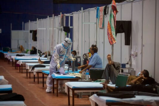 A health worker takes the temperature of a patient at a makeshift COVID-19 care center at an indoor sports stadium, in New Delhi, India, Saturday, Sept. 19, 2020. India has been reporting the highest single-day rise in the world every day for more than five weeks. Its expected to become the pandemics worst-hit country within weeks, surpassing the United States. (AP Photo/Altaf Qadri)