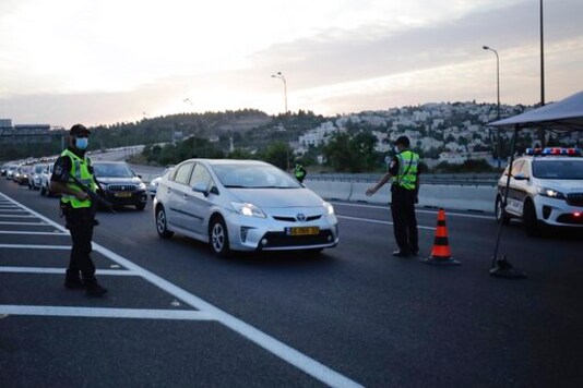 Israeli police officers check cars at a checkpoint during a three-week lockdown near Jerusalem, Sunday, Sept. 20, 2020. Israel went back into a full lockdown to try to contain a coronavirus outbreak that has steadily worsened for months. (AP Photo/Sebastian Scheiner)