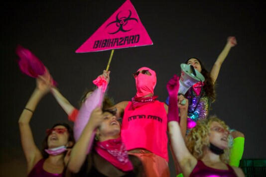 Protesters chant slogans and hold banners against Israeli Prime Minister Benjamin Netanyahu and the new coronavirus countrywide lockdown in Tel Aviv, Israel, Thursday, Sept. 17, 2020.  Netanyahu's government has imposed a three-week lockdown, beginning on Friday afternoon. (AP Photo/Ariel Schalit)